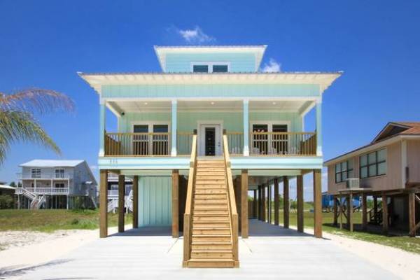 front view of house rental on the beach in gulf shores orange beach with spacious patio, blue paaint and staircase leading to the door