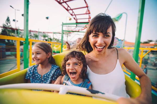 young woman and two young girls on a yellow roller coaster 