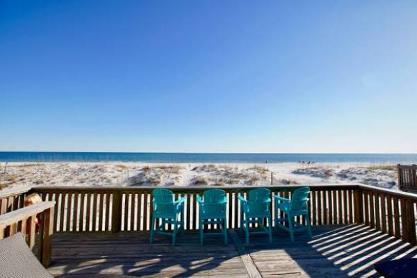 four turqouise chairs along a private patio overlooking the sand dunes and beaches of the alabama gulf coast on bluebird day