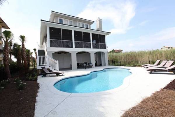 beach home rental with pool and patio area with lounge chairs and palm trees in gulf shores orange beach alabama