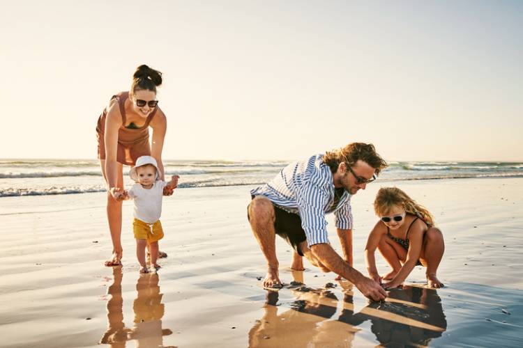 young family of four playing on a beach at sunset